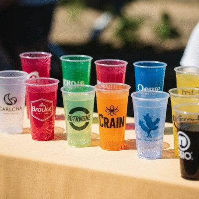 Custom plastic cups with various brand logos at an event