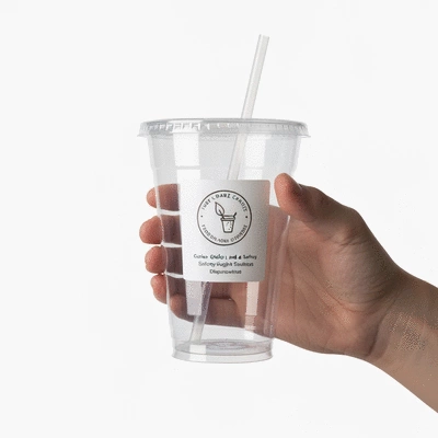 Hand holding a custom plastic cup with a clear label indicating food-grade and safety compliance