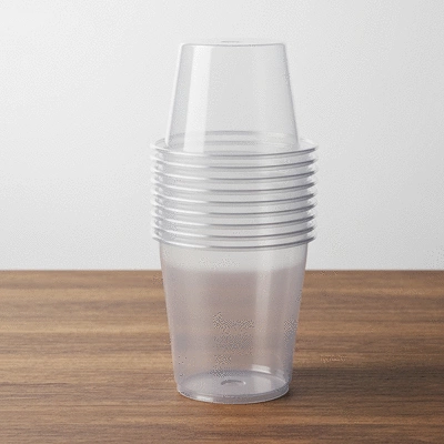 Stack of clear eco-friendly biodegradable plastic cups on a natural wood surface